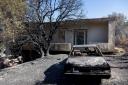 A burned out car is seen in the yard of a house after a wildfire at Keratea area, south east of Athens (AP Photo/Yorgos Karahalis)